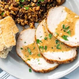 A closeup of three slices of pork with a golden sauce over the top.