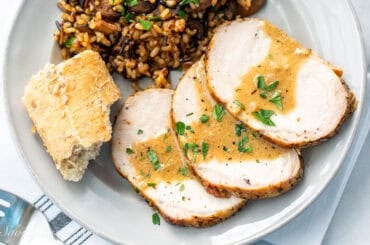 A closeup of three slices of pork with a golden sauce over the top.