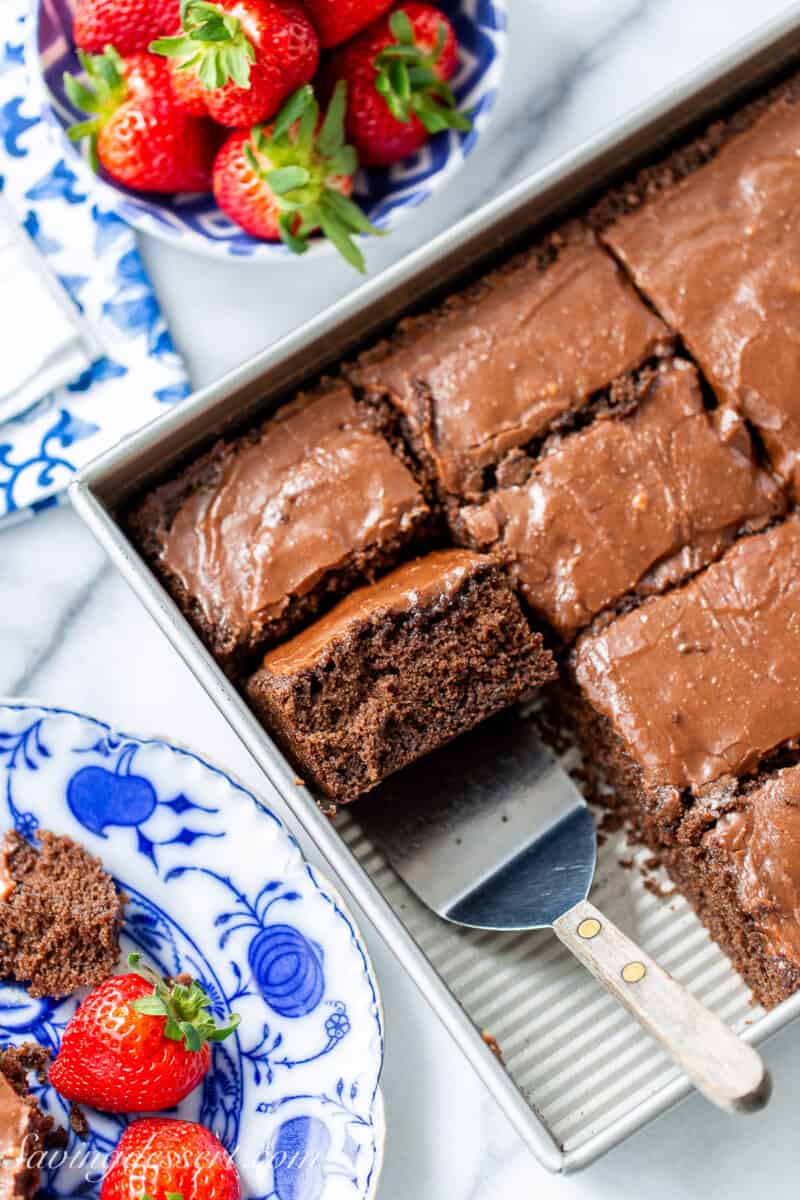 An overhead view of a pan of chocolate cake with several pieces sliced and one on a spatula.