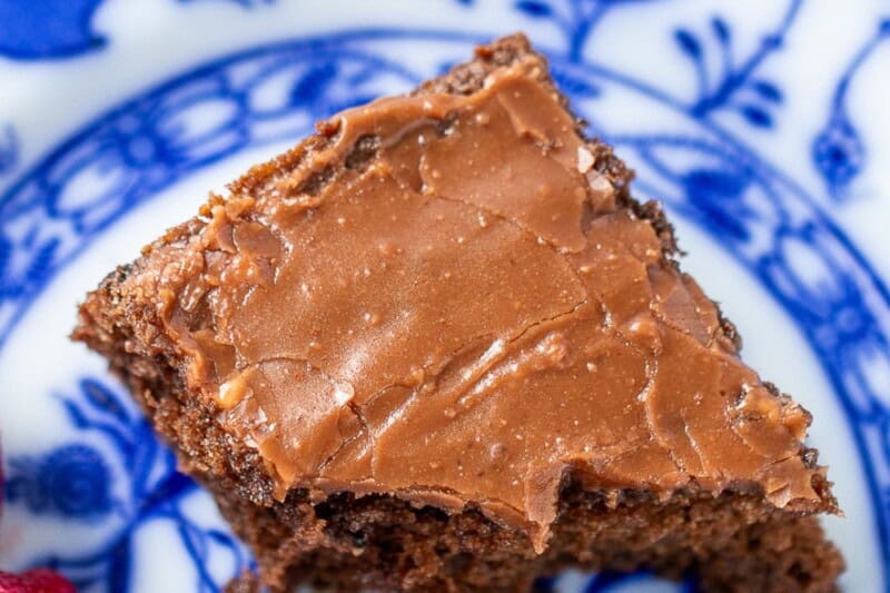 An overhead photo of a piece of buttermilk chocolate cake on a blue plate with strawberries on the side.