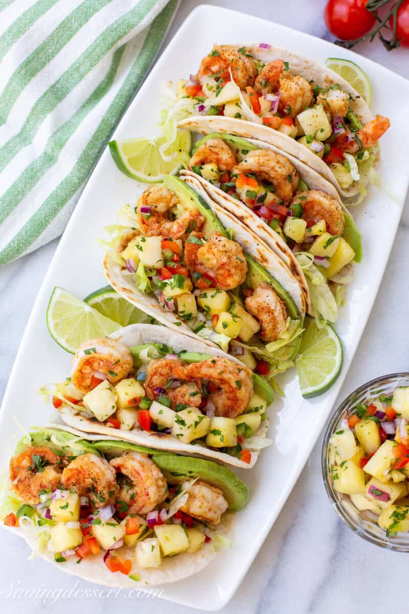 A long platter of shrimp tacos with salsa.
