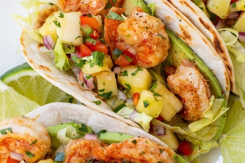 A platter of shrimp tacos topped with pineapple salsa, cilantro and avocado.