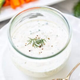 A jar of ranch dressing with fresh dill on top.