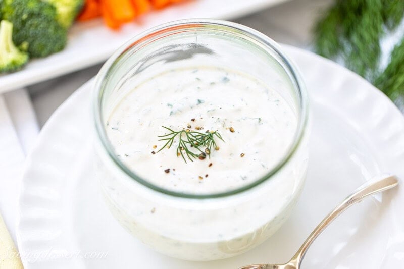 A jar of ranch dressing with fresh dill on top.