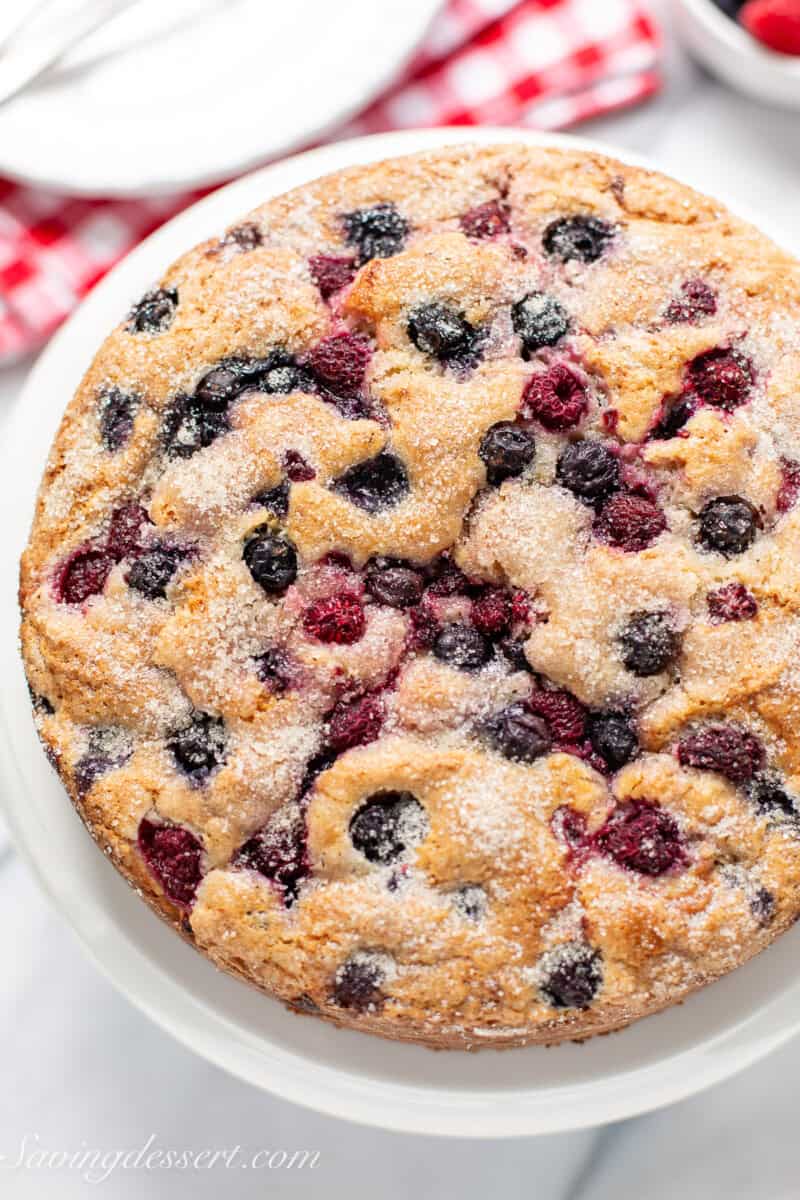 An overhead photo of a rustic red white and blue cake topped with raspberries and blueberries.
