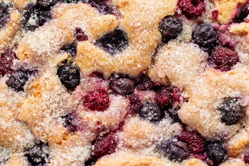 An overhead photo of a rustic, single layered berries studded cake on a cake stand.