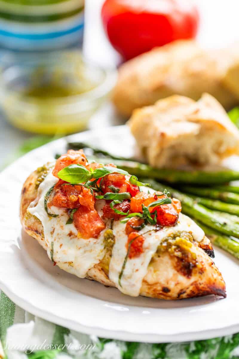 Chicken caprese on a plate with asparagus.
