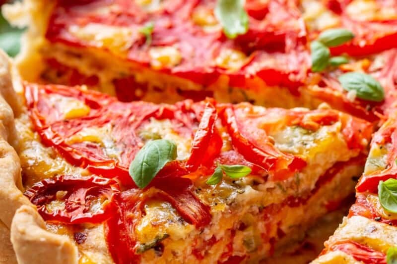 A closeup photo of a tomato pie with fresh basil on top.
