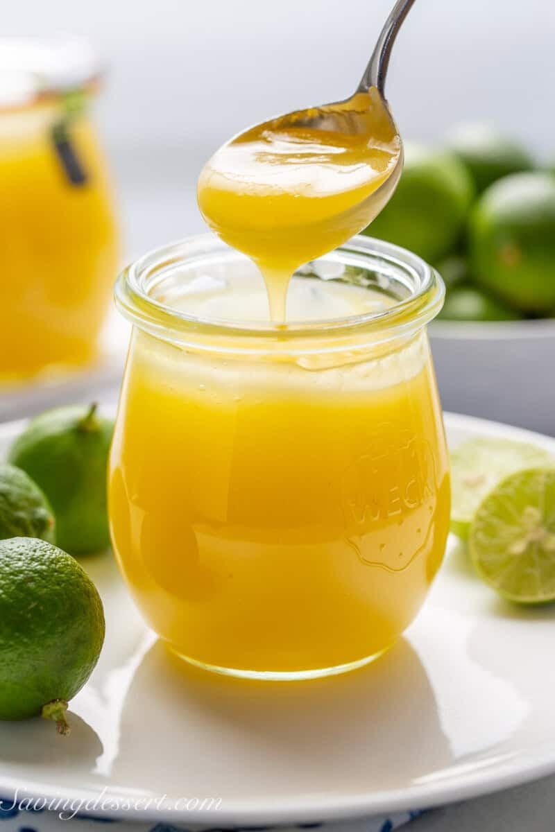 Key Lime curd being drizzled into a jar from a spoon.
