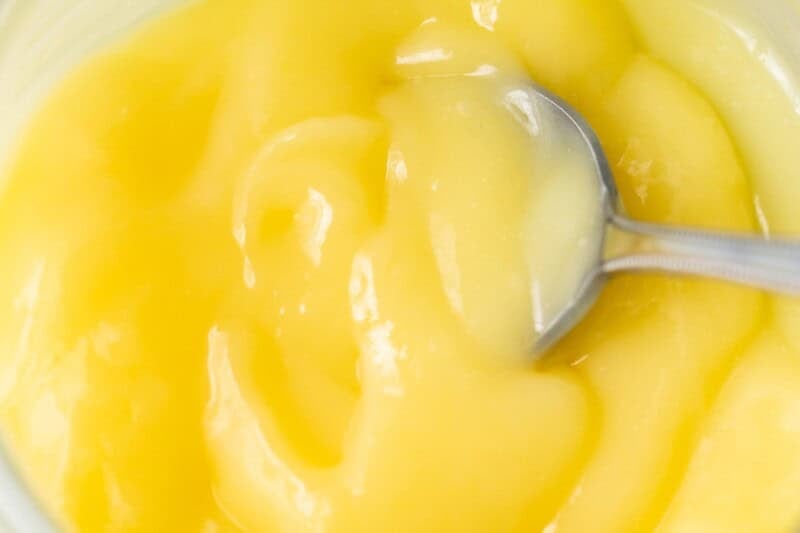 Thick Key Lime curd in a jar with a spoon.