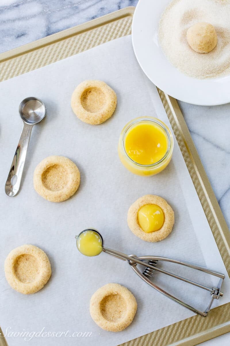 Key lime pie cookie dough balls on a baking sheet with curd in the middle.