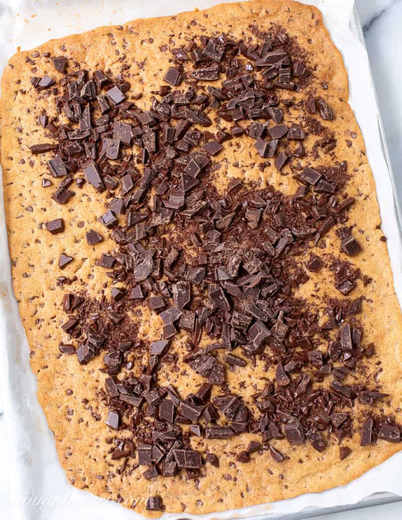 A full pan of thin and crispy cookie bark topped with chopped dark chocolate.
