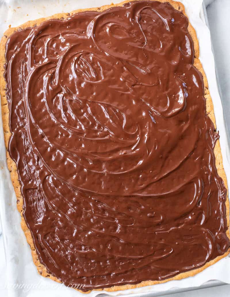 A pan sized thin chocolat chip cookie topped with melted dark chocolate.