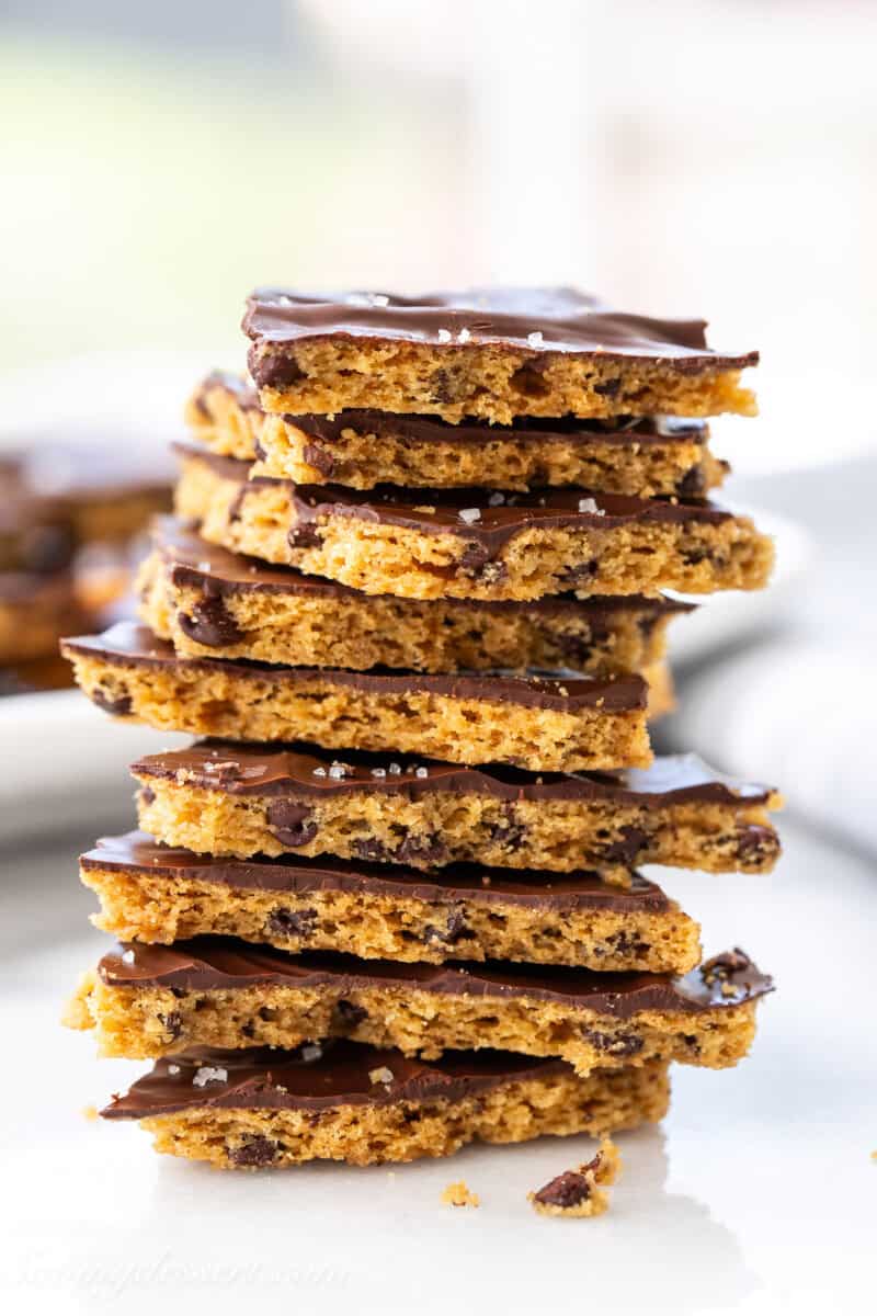 A side view of a stack of chocolate chip cookie bark topped with dark chocolate and sea salt.