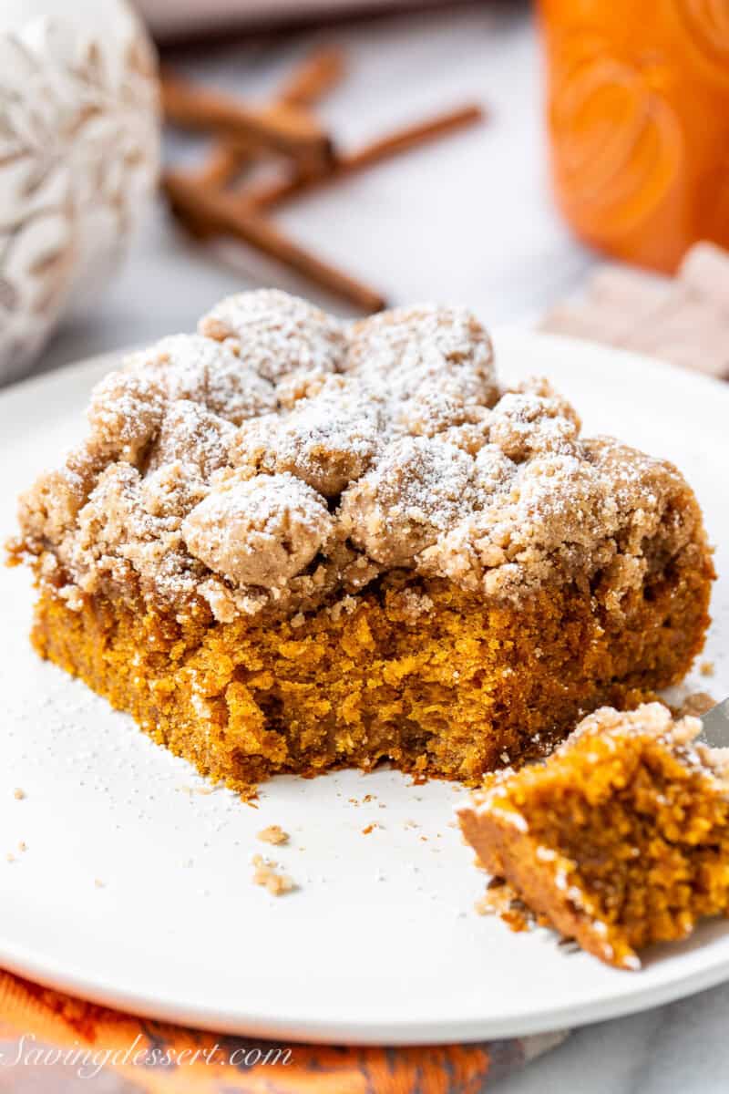 A slice of pumpkin crumb cake on a plate with the corner cut off.