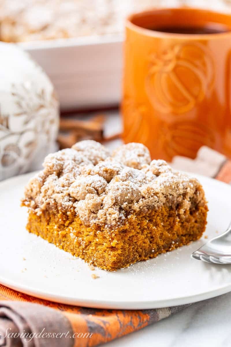Pumpkin Crumb Cake on a plate with a cup of coffee in the background.