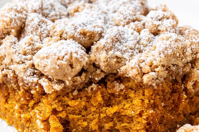 A piece of pumpkin crumb cake on a plate with the corner cut off by a fork.